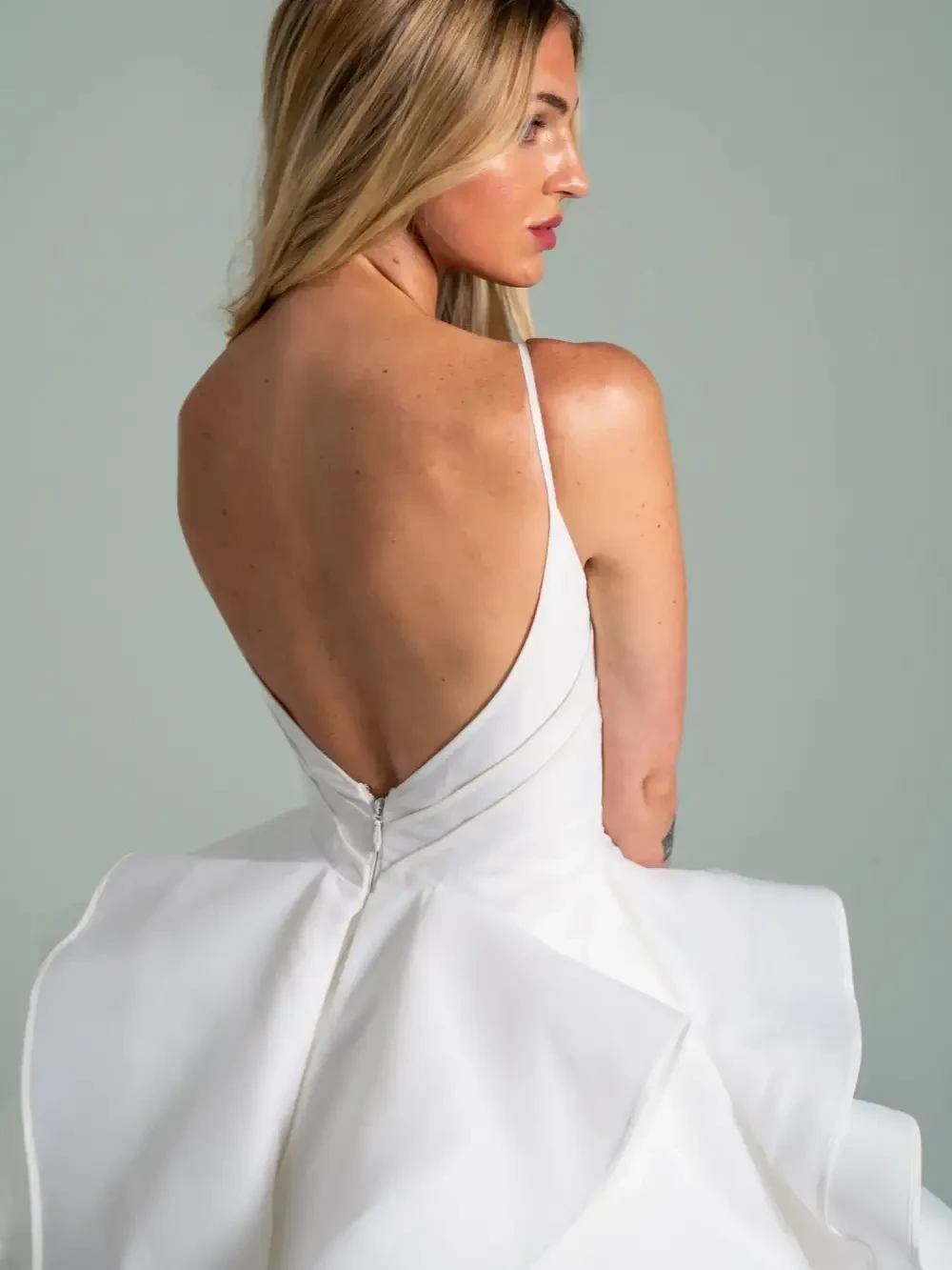 model is wearing a sleeveless open back bridal gown