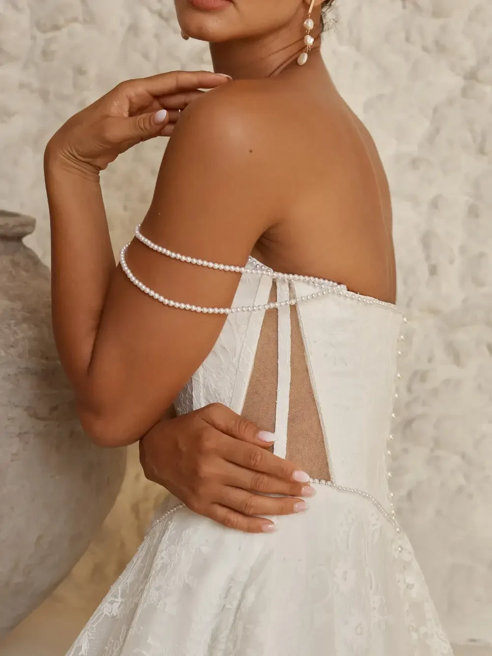 model is wearing a strapless bridal gown with draped pearls