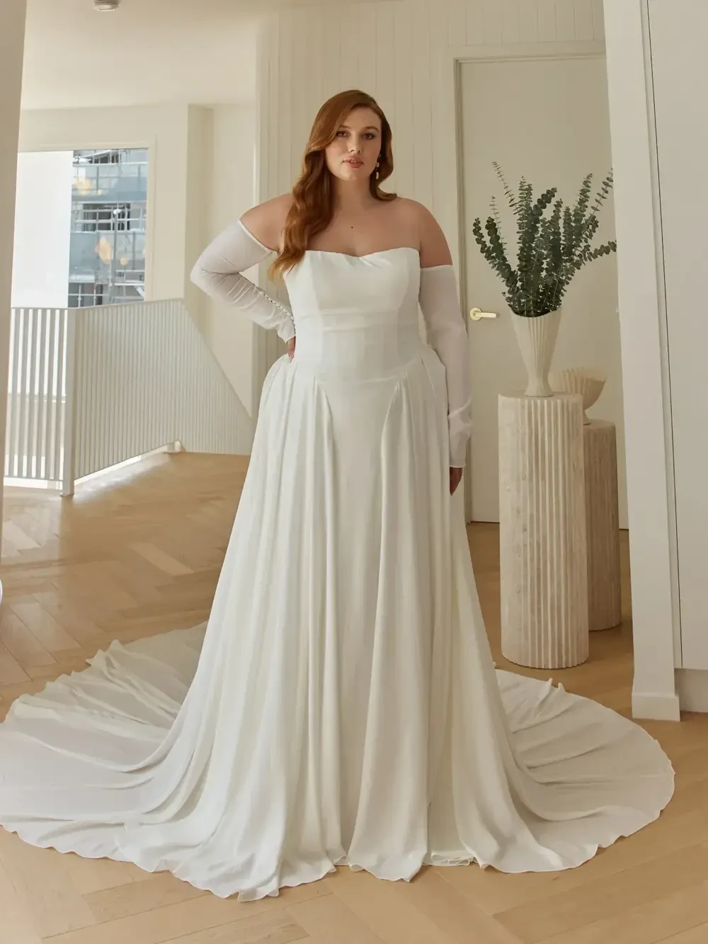 model is wearing a strapless bridal gown with detachable sleeves