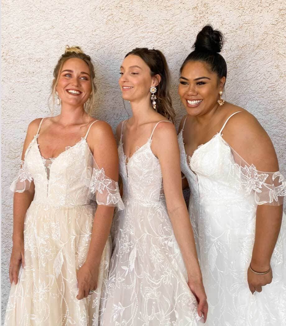 Smiling models wearing a white gowns. Mobile image